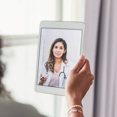 A female doctor offers an unrecognizable female patient advice during a telemedicine appointment.